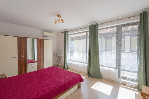 a bedroom with a red bed and large windows at Sea Garden Marina 3 in Varna City