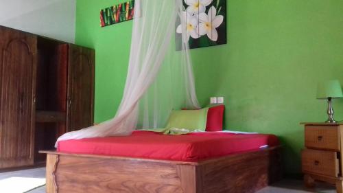a bedroom with a bed with red sheets and a green wall at Belle Amie Self Catering in La Digue