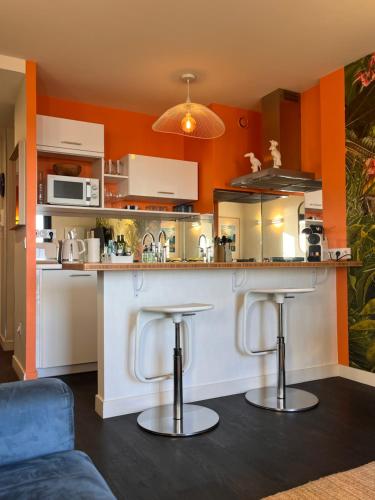 une cuisine avec un îlot et deux tabourets de bar dans l'établissement Emeraude, pleine vue de mer, à Saint-Malo