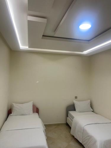 two beds in a room with white walls at coastal charm harhoura in Temara