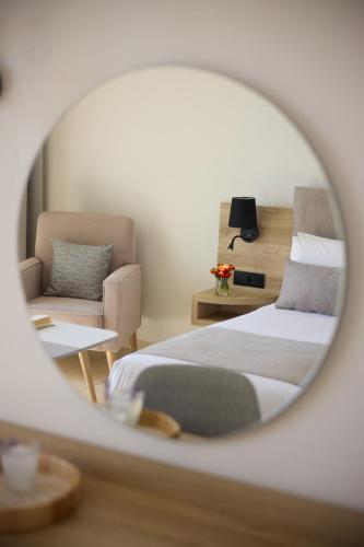 a bedroom with a bed and a chair and a mirror at Kiotari Bay in Kiotari