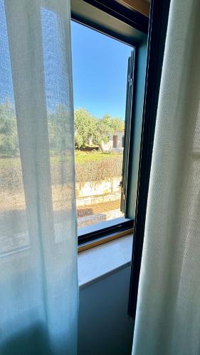 a window with white curtains and a view of a field at Ibisco Hotel in Rodi Garganico