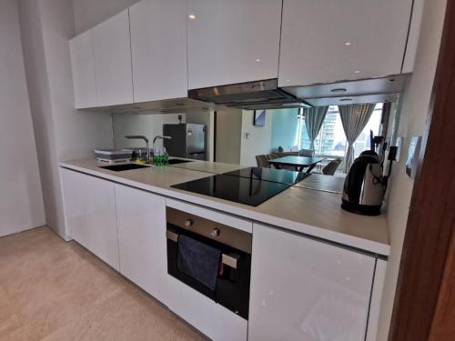 a kitchen with white cabinets and a stove top oven at Sky Suites KLCC By Star Apartment in Kuala Lumpur