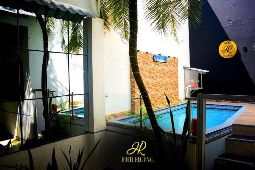 a house with a swimming pool and a palm tree at Hotel Regional in La Dorada