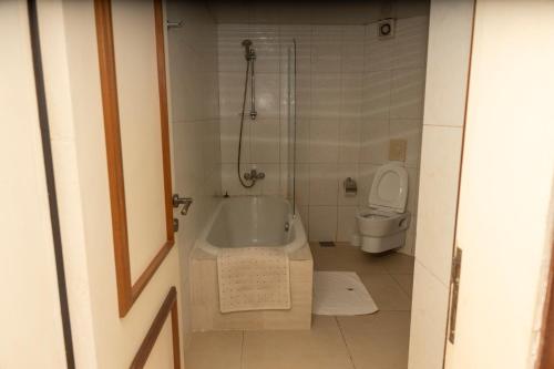 a bathroom with a bath tub and a toilet at Hotel Barmoi in Freetown