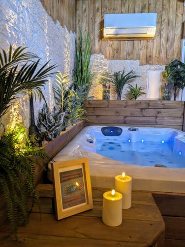 a jacuzzi tub in a room with candles and plants at Les Spas de la mer, Appart&Spa Canopée, 100m de la plage, Love Room in Le Grau-du-Roi