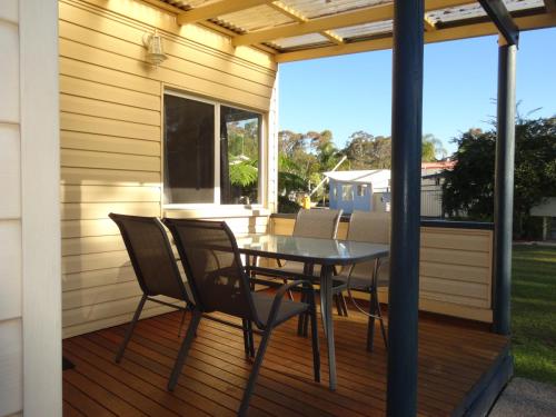 a patio with a table and chairs on a deck at Caseys Beach Holiday Park in Sunshine Bay