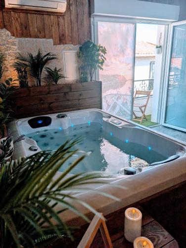 a jacuzzi tub in a room with a window at Les Spas de la mer, Appart&Spa Canopée, 100m de la plage, Love Room in Le Grau-du-Roi