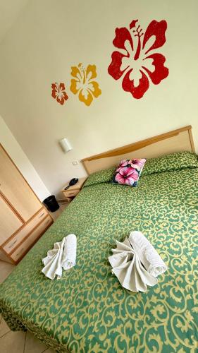 a bedroom with a green bed with two slippers on it at Ibisco Hotel in Rodi Garganico