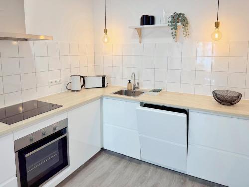 a kitchen with white cabinets and a sink and a stove at Deichstadt Apartments in Neuwied