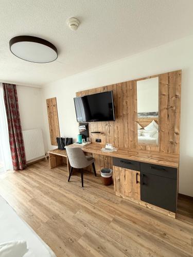 a room with a desk with a television and a chair at Hotel Achentalerhof in Achenkirch