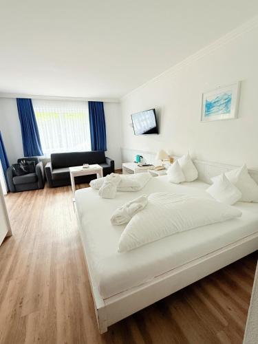 a bedroom with a large white bed and a living room at Hotel Achentalerhof in Achenkirch