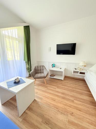 a white living room with a couch and a table at Hotel Achentalerhof in Achenkirch