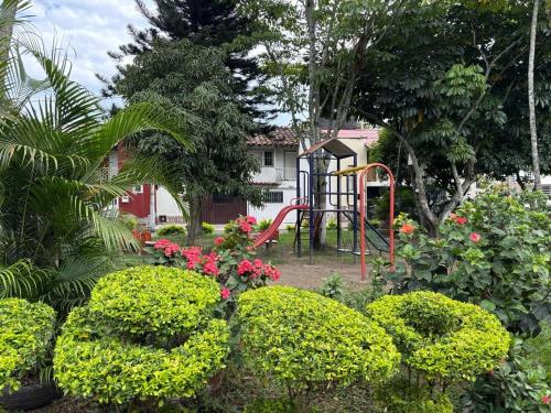 a playground in a garden with bushes and flowers at cozy house in Buga Valle in Buga