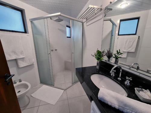 a bathroom with a shower and a sink and a toilet at Hotel Germânia in Joinville