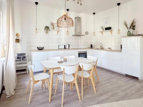a kitchen with white cabinets and a table and chairs at Deichstadt Apartments in Neuwied