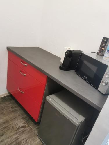 a desk with a red drawer and a microwave at GARSONIERĂ in Arad