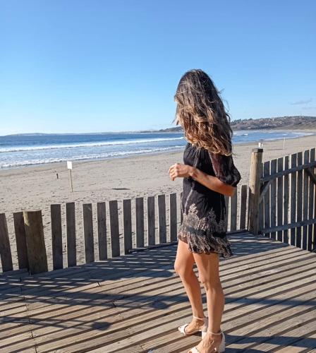 a woman standing on a boardwalk at the beach at Hotel Trocadero in Concón