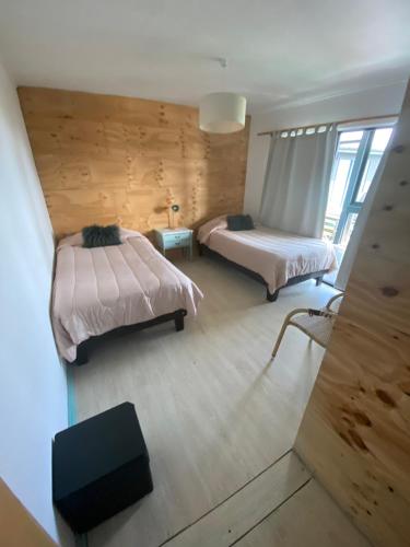 two beds in a room with wooden walls at Hotel Trocadero in Concón