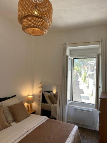 une chambre avec un lit, une fenêtre et un lustre dans l'établissement La Maisonnette, à Nîmes