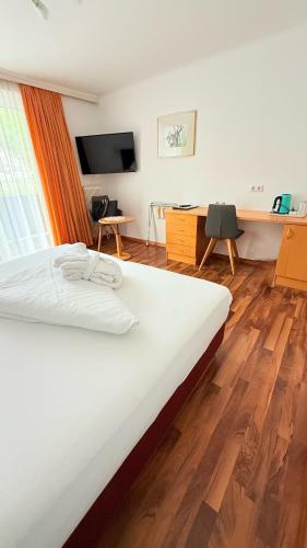 a large bed in a room with a wooden floor at Hotel Achentalerhof in Achenkirch