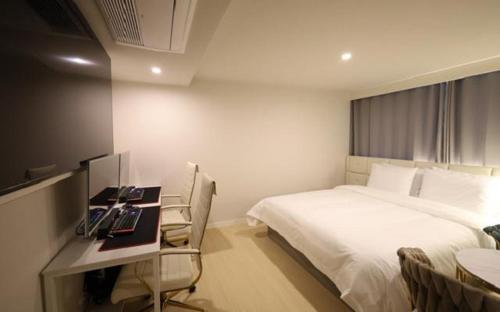 a hotel room with a bed and a desk with a computer at Masan Den Basta Gyeongnam Uni in Changwon