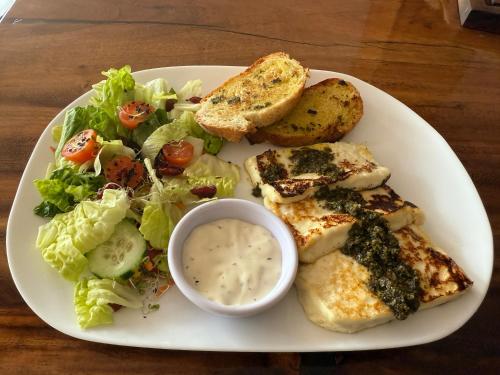 a plate of food with a salad and bread and a bowl of sauce at Hotel Cinco Diamantes in Atotonilco el Alto