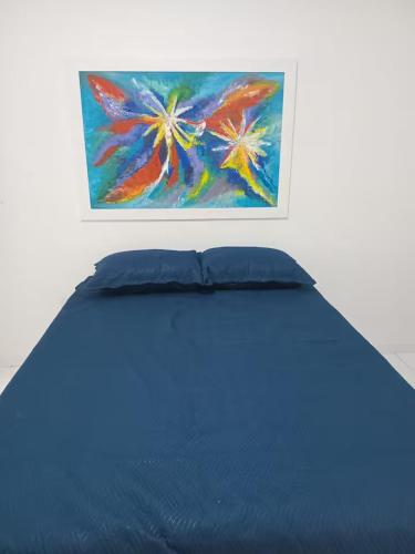 a bed in a room with a painting on the wall at Aconchegante Casa em Gravatá in Gravatá
