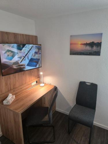 a desk in a room with a chair and a television at Bodensee Sunshine Zimmer & Apts. in Uhldingen-Mühlhofen