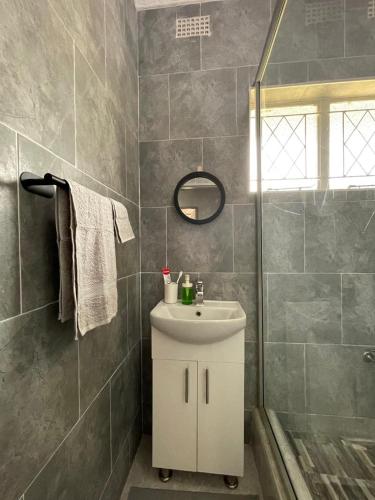 a bathroom with a white sink and a shower at Hulley Homes- Escape to Beautiful Mountain Views in Umtali