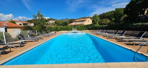 une piscine avec des chaises longues et une maison dans l'établissement Studio Dolce & Vita C2 vue mer avec piscine, à Propriano
