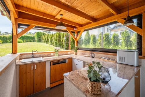 a kitchen with wooden cabinets and a large window at Orlická přehrada Wellness Chata Hřebeny in Milešov