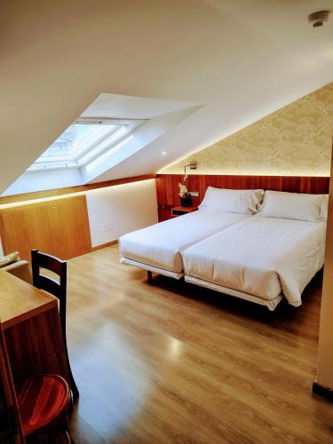 a bedroom with a large white bed with a skylight at Pensión O Códice by Moradas Nieto in Santiago de Compostela