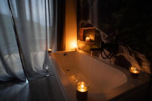 a bathroom with a tub with candles and a window at Bunkier House in Niedźwiada