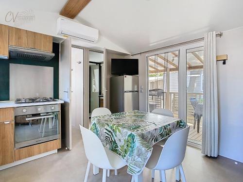 une cuisine et une salle à manger avec une table et des chaises dans l'établissement Mobil-home VO 05 à Vias - La Carabasse - Camping Siblu avec Piscine, à Vias