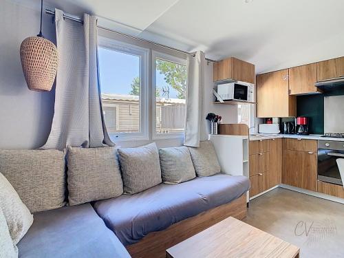 un salon avec un canapé et une fenêtre dans l'établissement Mobil-home VO 05 à Vias - La Carabasse - Camping Siblu avec Piscine, à Vias