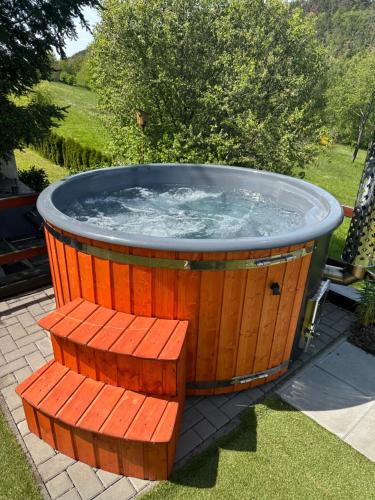 a large wooden hot tub with a bench around it at Orlická přehrada Wellness Chata Hřebeny in Milešov