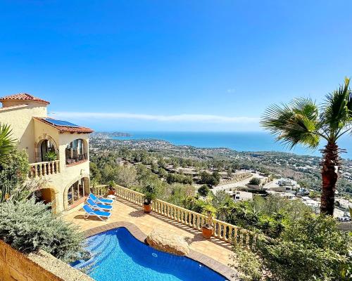 a house with a swimming pool and a palm tree at Villa La Mansion in Benissa