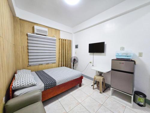 a bedroom with a bed and a desk and a tv at Happy Homes Guest House in Legazpi