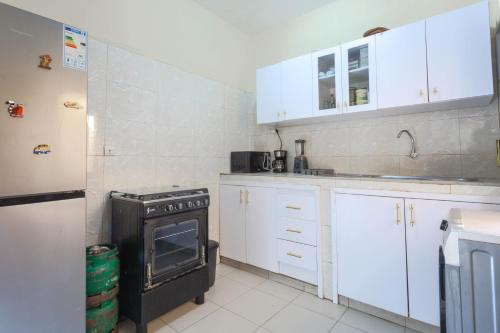 a small kitchen with white cabinets and an oven at Logement paisible au cœur de Dakar, chambre avec bureau et salle de bain dans un appartement partagé in Dakar