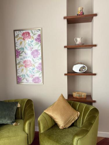 a living room with two green chairs and a plate at Casa Deco Hotel Boutique in Cochabamba