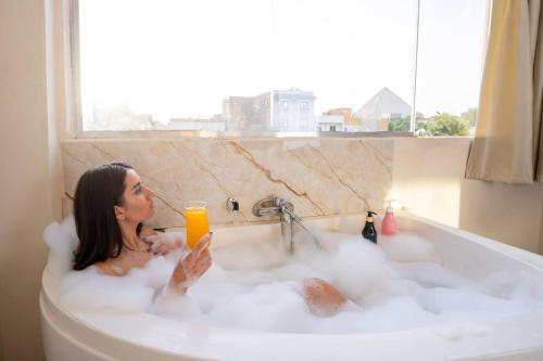 カイロにあるmajestic hotel pyramids viewの女性がバスタブに座ってオレンジジュースを飲む
