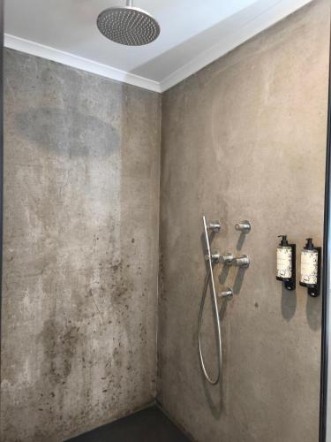 a shower in a bathroom with a concrete wall at Cá Por Casa Pico-Faia in Prainha de Baixo