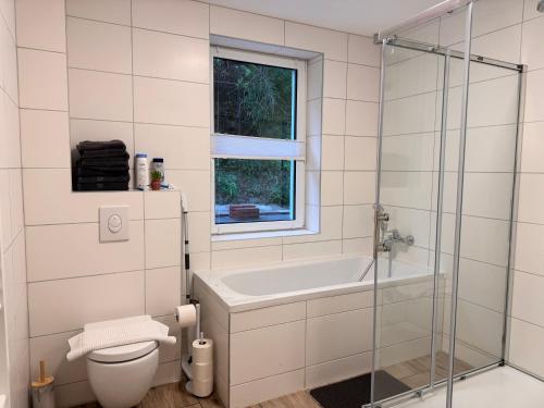 a bathroom with a tub and a toilet and a window at Ferienwohnung Hubertus in Blankenstein