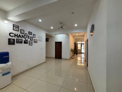 a hallway with a white wall with pictures on it at Pine Haven dharamshala in Dharmsala
