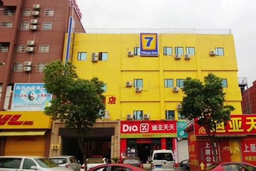 un bâtiment jaune dans une rue de la ville avec des voitures dans l'établissement 7Days Inn Shanghai Hong Mei South Road Branch, à Shanghai