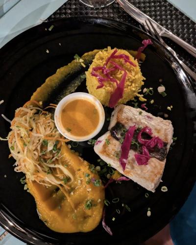 a black plate of food with a sandwich and sauce at Guadeloupe 5 Étoiles Front de Mer Rénové 2025 in Saint-François