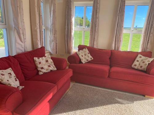 a red couch in a living room with windows at Cranagh House, Kinvara. in Loughcurra