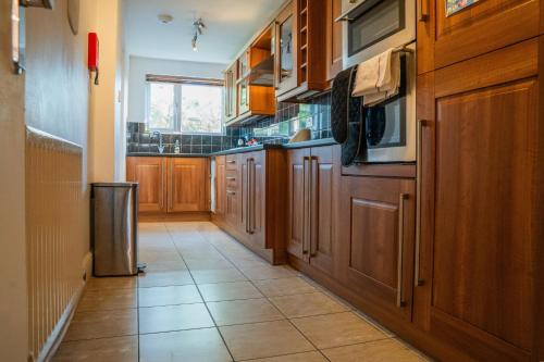 a kitchen with wooden cabinets and a tile floor at Berry Mansions - Comfort & Style in Wyken