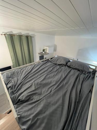 un lit avec un drap gris dessus dans une chambre dans l'établissement Ô Cocon d Océane, à Nîmes